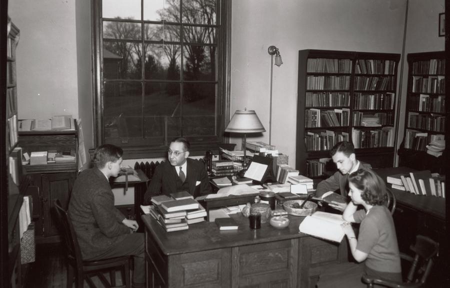 Harry Caplan at desk with three students