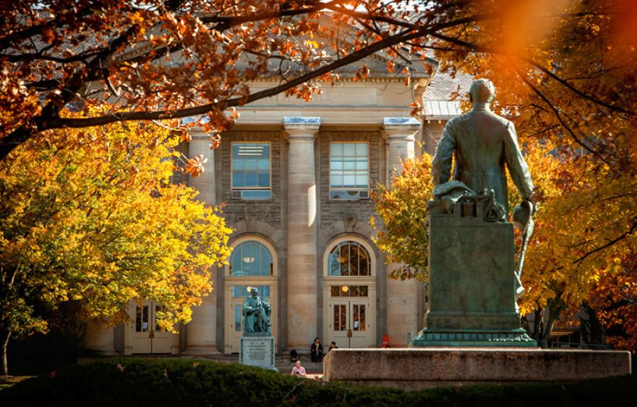 Ezra Cornell statue facing A.D. White statue and Goldwin Smith Hall, fall color on the trees