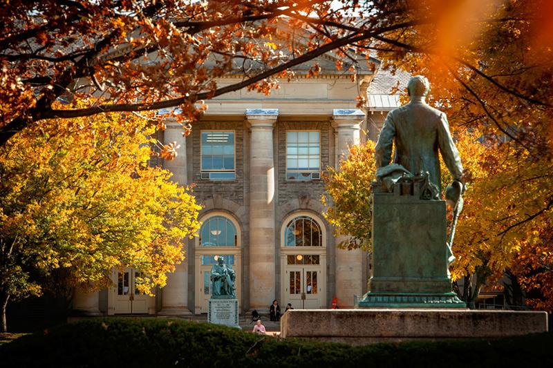 Ezra Cornell statue facing A.D. White statue and Goldwin Smith Hall, fall color on the trees